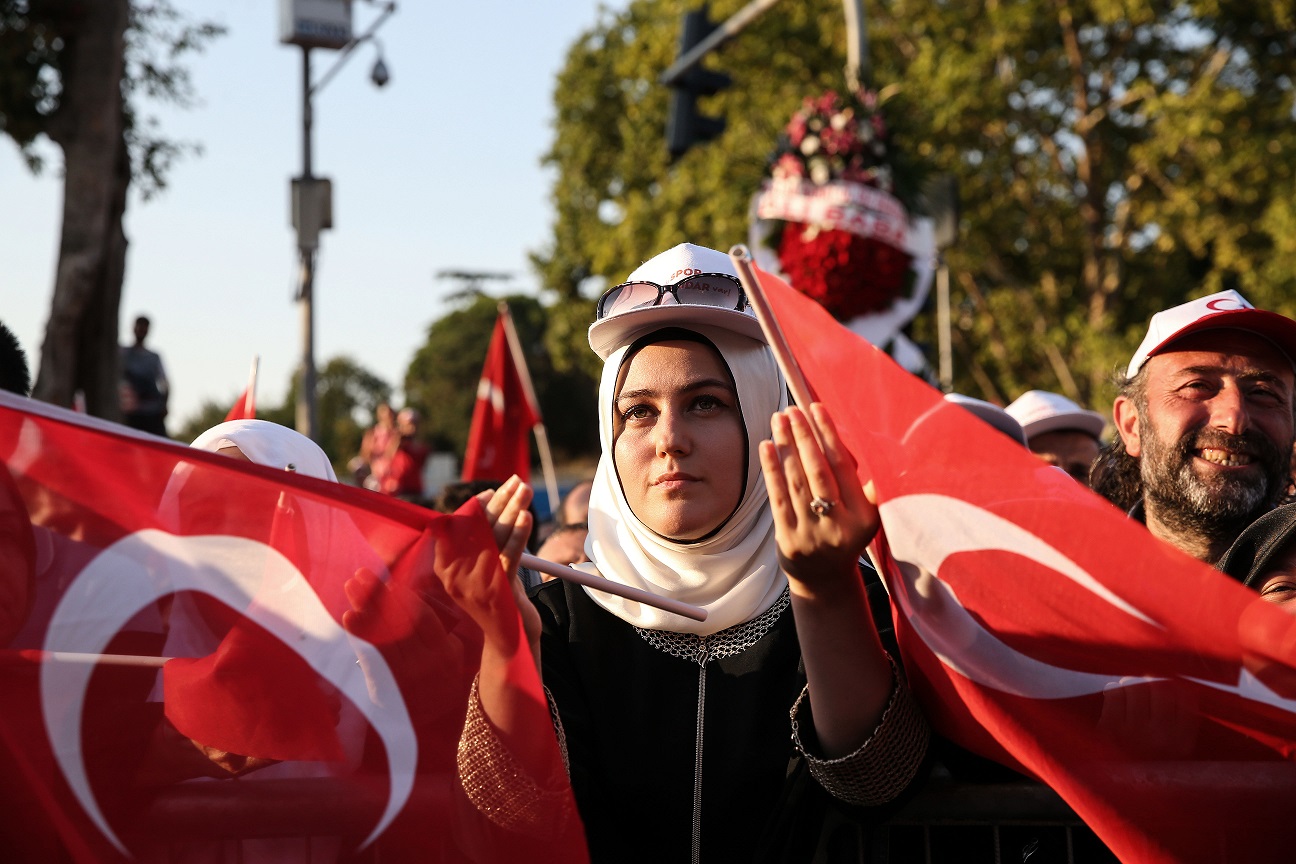 A citizen praying with a Turkish flag.